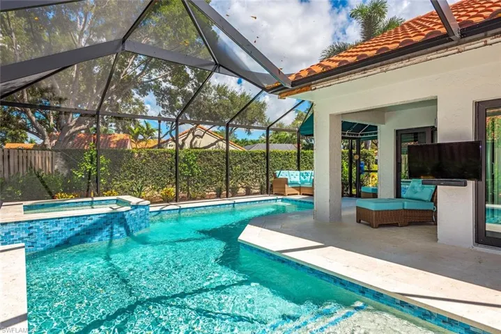 View of swimming pool featuring a patio area, glass enclosure, a sunroom, and a pool with connected hot tub