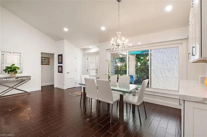 Dining space with dark wood-type flooring, recessed lighting, a chandelier, and vaulted ceiling