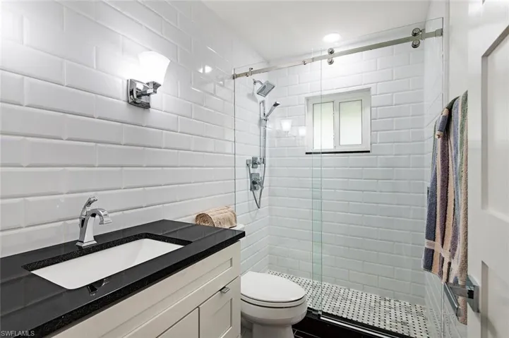 Full bath featuring a stall shower, vanity, tile walls, and backsplash