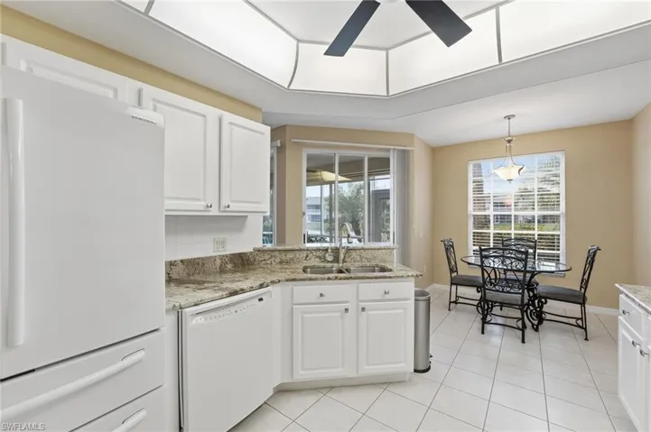 The kitchen boasts fabulous views of the lake and fountain, and features granite countertops, white cabinetry, white appliances, and a crisp white backsplash.