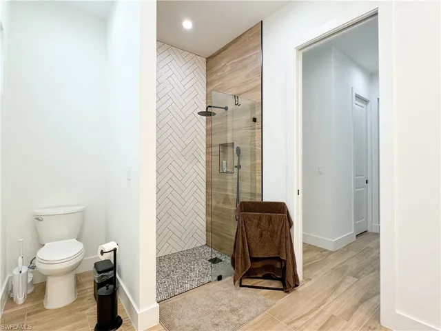 Bathroom with hardwood / wood-style floors, toilet, and tiled shower