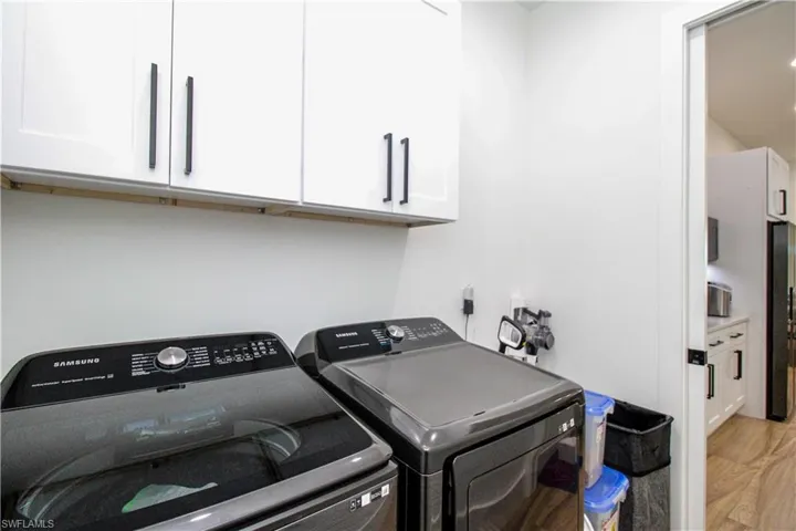 Clothes washing area with cabinets, light hardwood / wood-style floors, and washing machine and clothes dryer