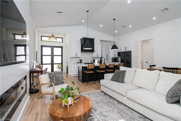 Living room with light wood-type flooring, sink, and high vaulted ceiling