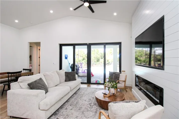 Living room with ceiling fan, light hardwood / wood-style flooring, and high vaulted ceiling