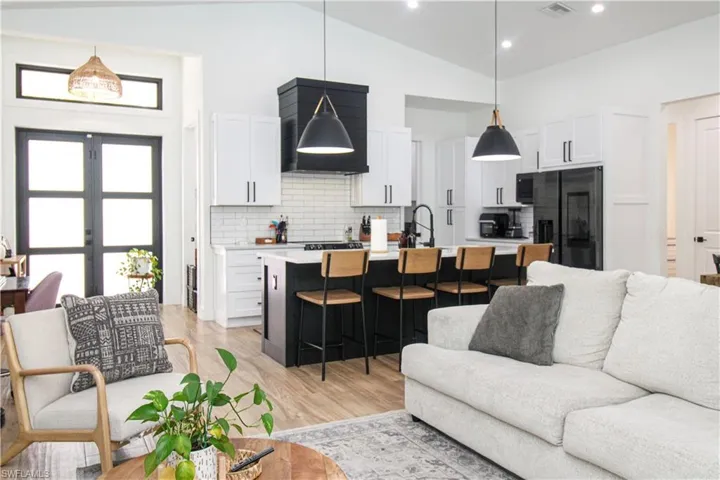 Living room with high vaulted ceiling, light wood-type flooring, and sink