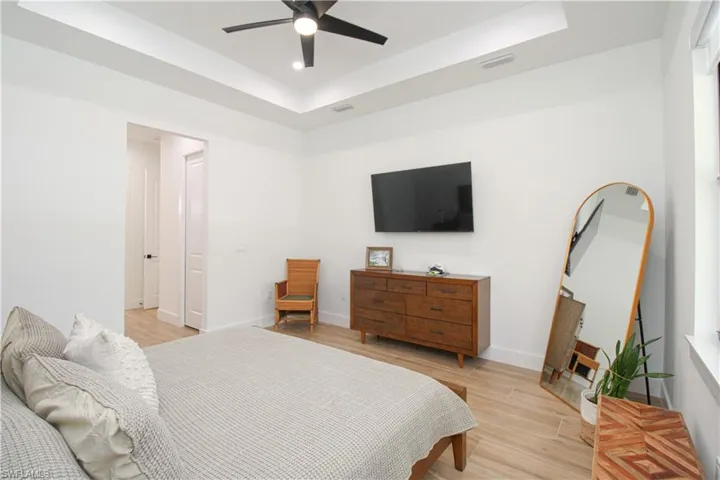 Bedroom featuring light wood-type flooring, a tray ceiling, and ceiling fan