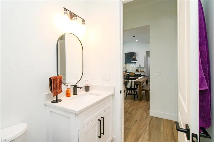 Bathroom with decorative backsplash, vanity, toilet, and wood-type flooring