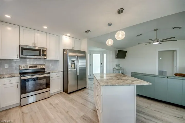 Spacious kitchen featuring white cabinetry, stainless steel appliances, and wood-finish flooring