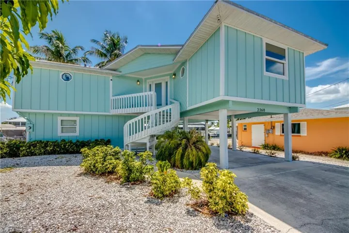 Coastal-style elevated residence featuring turquoise vertical siding and white trim