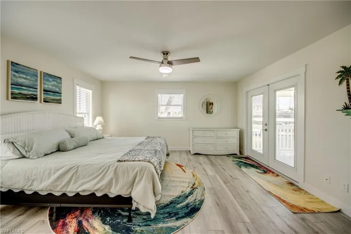 Spacious room featuring wood-finish flooring, light-toned walls, and a ceiling fan with integrated lighting
