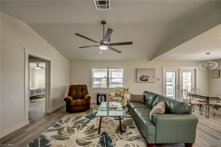 Open concept living area featuring vaulted ceilings, wood-finish flooring, and white trim throughout