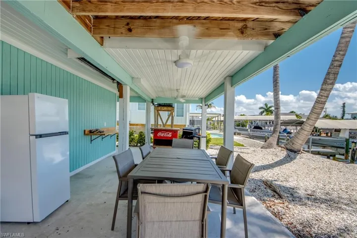 Covered outdoor patio with a concrete floor, light blue siding, and exposed natural wood beams