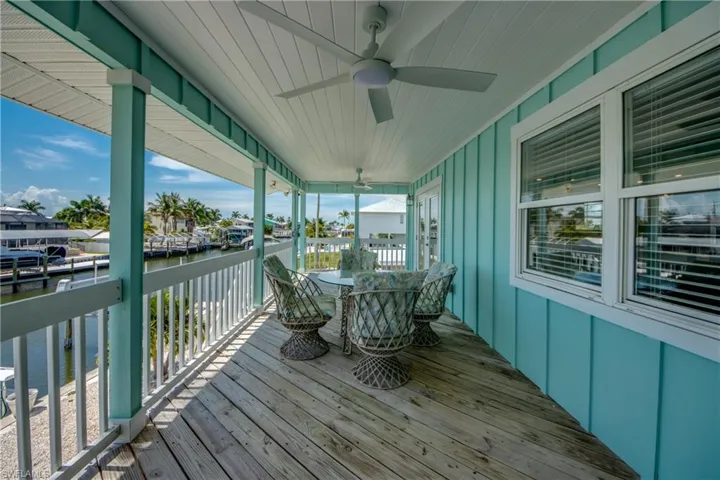 Expansive outdoor deck featuring wood-finish flooring, a white railing, and a tongue-and-groove ceiling with a ceiling fan