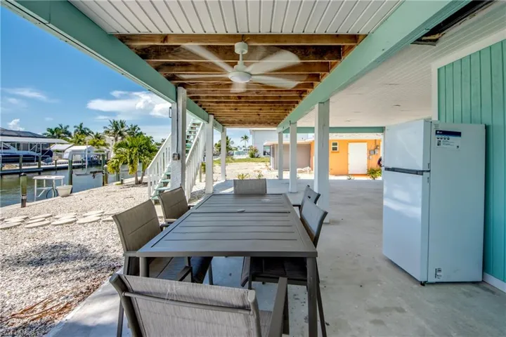 Covered patio area featuring a dining table with seating, exposed wood beam ceiling, and a ceiling fan