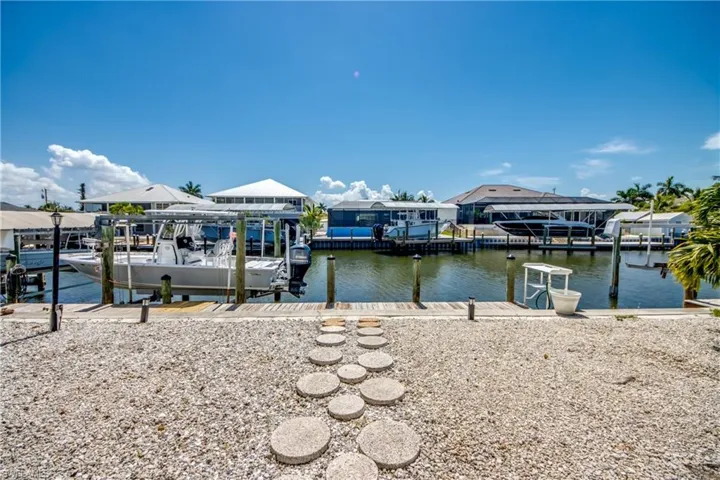Waterfront property featuring a private boat dock with lift, channel access, and a gravel yard with stepping stones