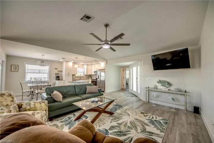 Expansive living area featuring vaulted ceilings, wood-finish flooring, and a modern ceiling fan
