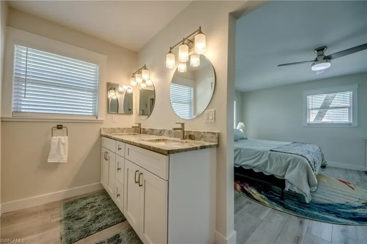 Dual vanity with undermount sinks, stone countertop, and two framed round mirrors