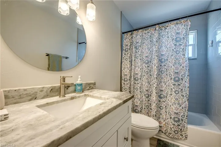 Bathroom vanity featuring a rectangular undermount sink, stone countertop, and brushed nickel faucet