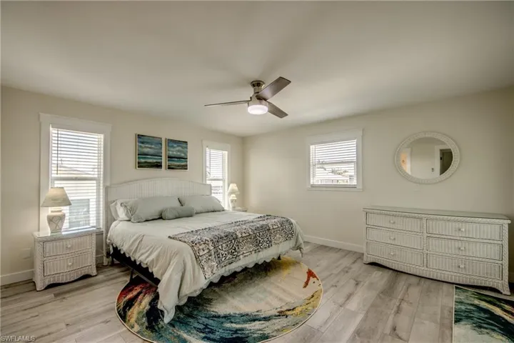 Spacious room featuring wood-finish flooring, multiple windows with blinds, and a ceiling fan with integrated lighting