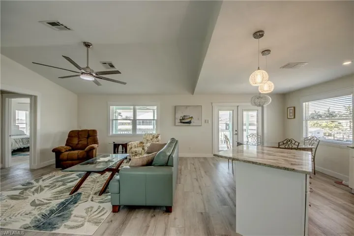 Open-concept living space featuring wood-finish flooring, vaulted ceilings, and a contemporary ceiling fan