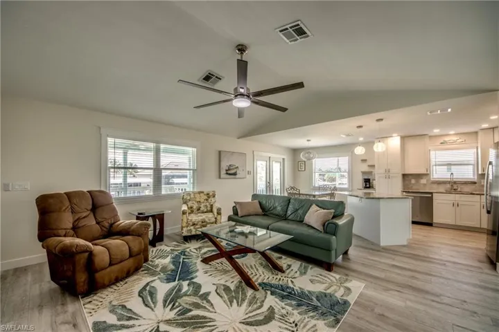Open-concept living space featuring wood-finish flooring, vaulted ceilings, and recessed lighting
