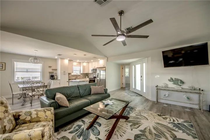 Open-concept living space featuring wood-finish flooring, a vaulted ceiling with a modern ceiling fan, and recessed lighting
