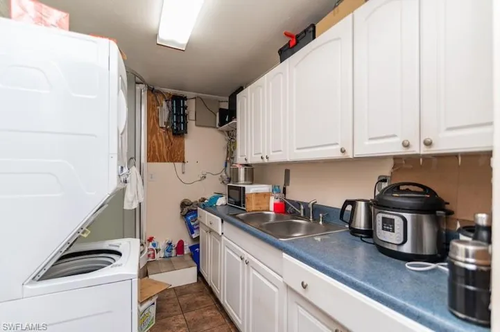 Kitchen featuring estacked washer and dryer, white cabinetry, and dark countertops