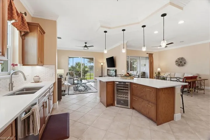 Kitchen featuring open floor plan, ceiling fan, pendant lighting, brown cabinets, and ornamental molding