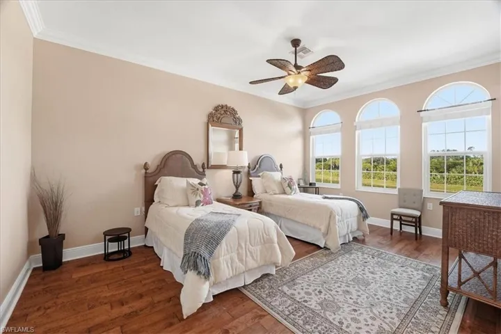 Bedroom featuring dark wood-type flooring, crown molding, and ceiling fan