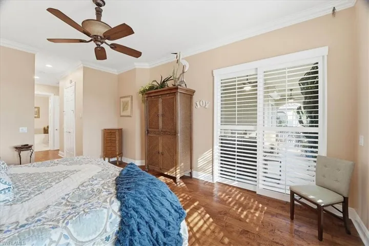 Bedroom featuring hardwood / wood-style flooring, ornamental molding, a ceiling fan, and ensuite bathroom