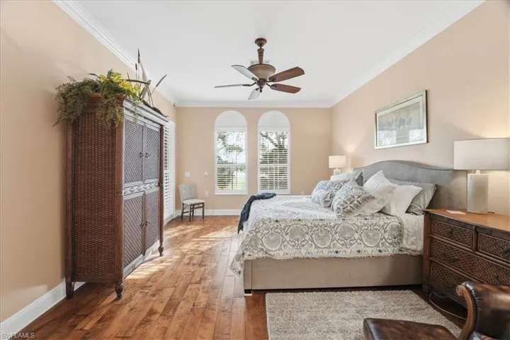 Bedroom with crown molding, light wood-style floors, and ceiling fan