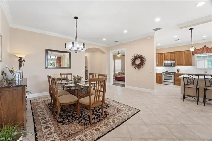 Dining room with arched walkways, crown molding, a chandelier, recessed lighting, and a ceiling fan