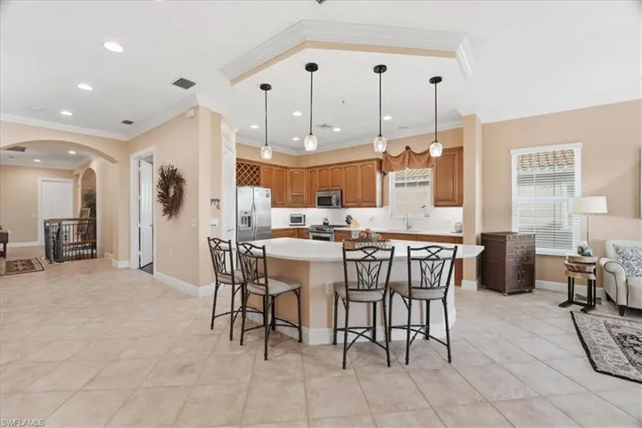 Kitchen featuring light countertops, arched walkways, a center island, a breakfast bar, and crown molding