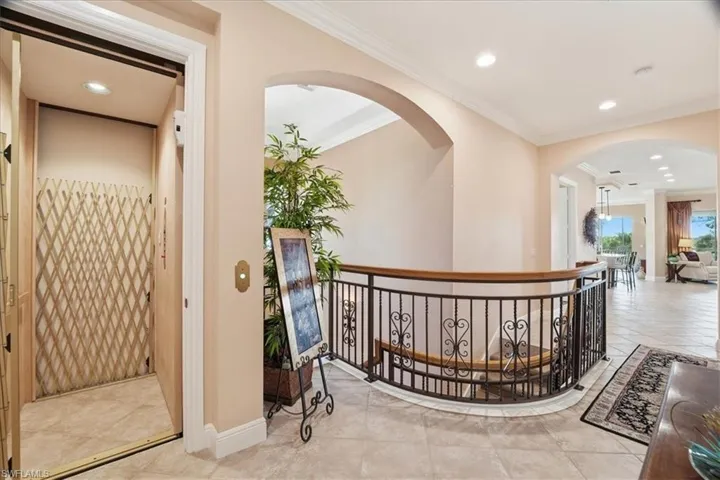 Hallway with elevator, recessed lighting, crown molding, arched walkways, and tile patterned floors