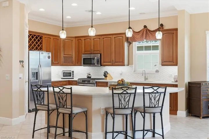 Kitchen featuring a kitchen bar, tasteful backsplash, appliances with stainless steel finishes, ornamental molding, and recessed lighting