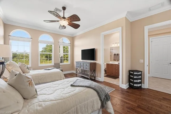 Bedroom featuring dark wood-style floors, ornamental molding, a ceiling fan, and ensuite bathroom