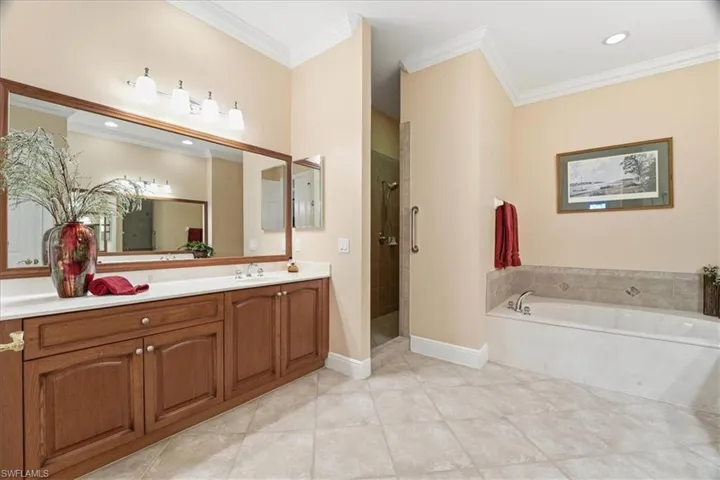 Bathroom with ornamental molding, vanity, a garden tub, a stall shower, and light tile patterned flooring