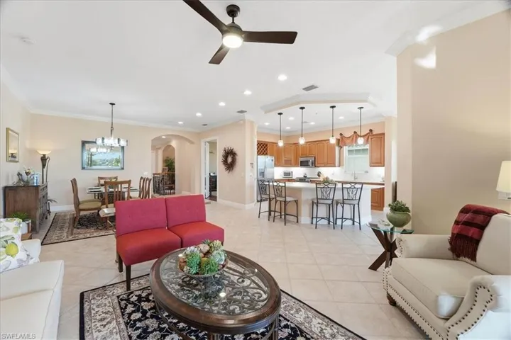 Living room featuring arched walkways, crown molding, a ceiling fan, recessed lighting, and a chandelier
