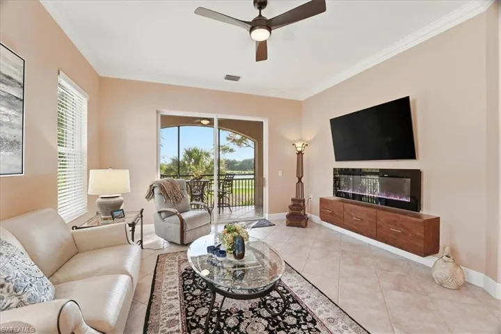 Tiled living area featuring a ceiling fan and ornamental molding