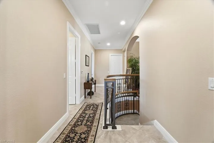Corridor with an upstairs landing, arched walkways, crown molding, light tile patterned floors, and recessed lighting