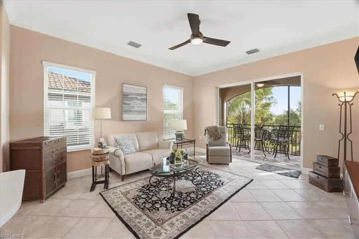 Living room featuring crown molding, light tile patterned floors, a ceiling fan, and healthy amount of natural light