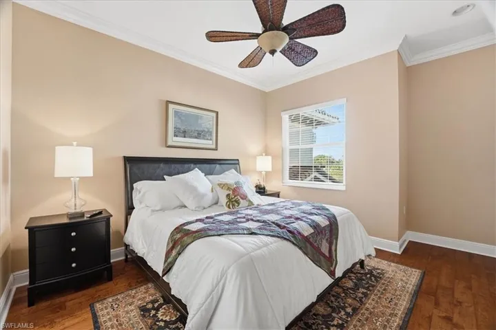 Bedroom featuring dark wood-style floors, ornamental molding, and a ceiling fan