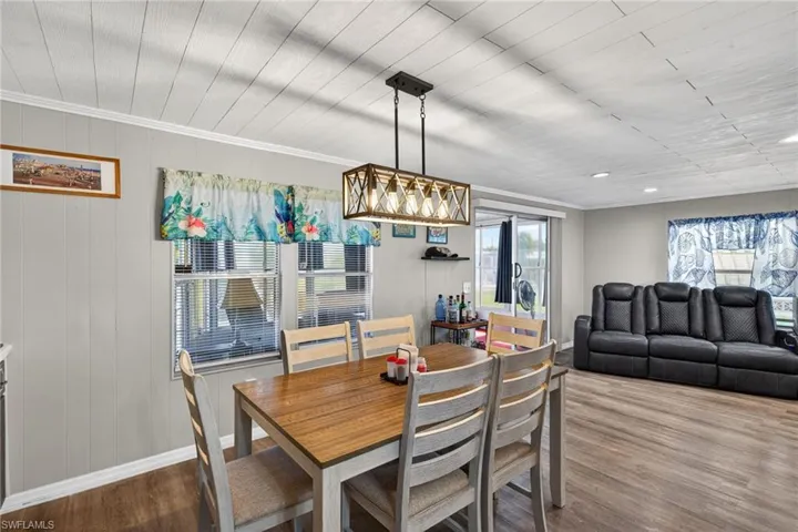 Dining room with dark wood finished floors, wood walls, and crown molding