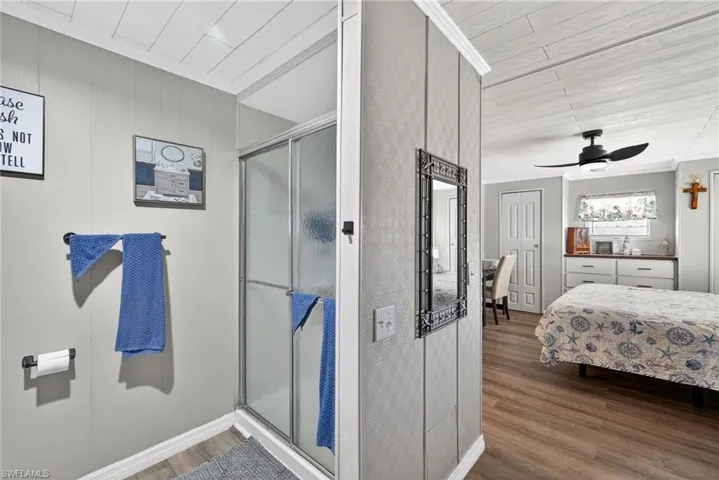 Ensuite bathroom with crown molding, a stall shower, wood finished floors, and a ceiling fan