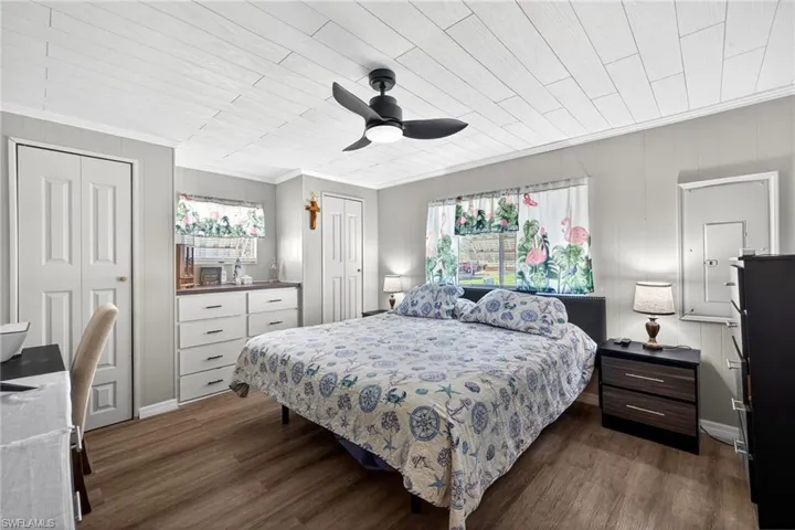 Bedroom featuring wood-type flooring, a ceiling fan, multiple closets, ornamental molding, and wood ceiling