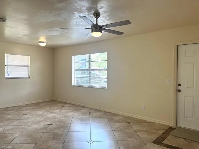Empty room with light tile patterned floors and a ceiling fan