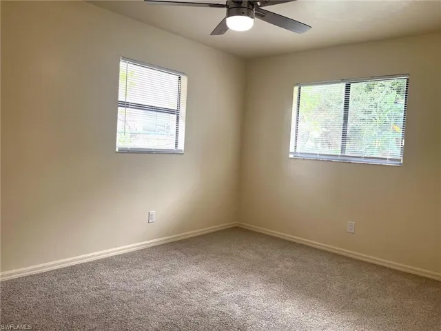 Carpeted spare room featuring baseboards and a ceiling fan