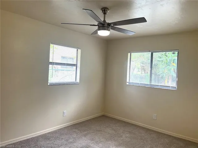 Carpeted empty room featuring baseboards and ceiling fan