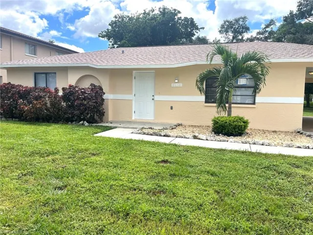 View of front of property with a front lawn, stucco siding, and roof with shingles