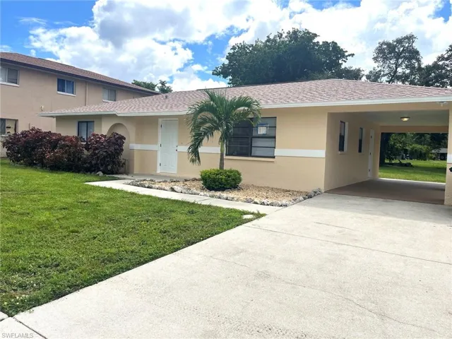 View of front of home with a front yard, stucco siding, concrete driveway, and roof with shingles